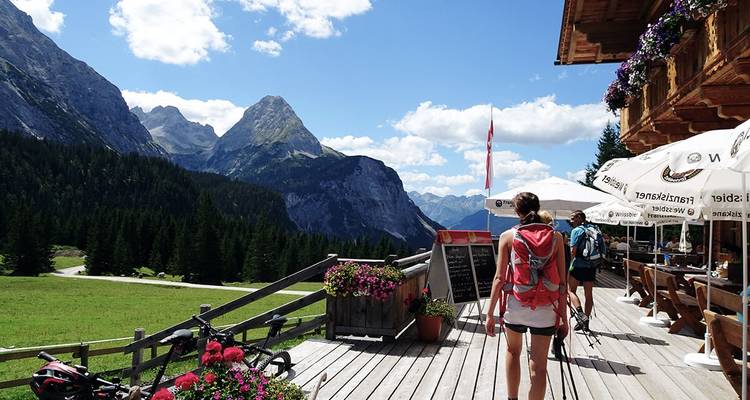 Randonneur marchant sur une terrasse avec vue sur les montagnes et le restaurant.