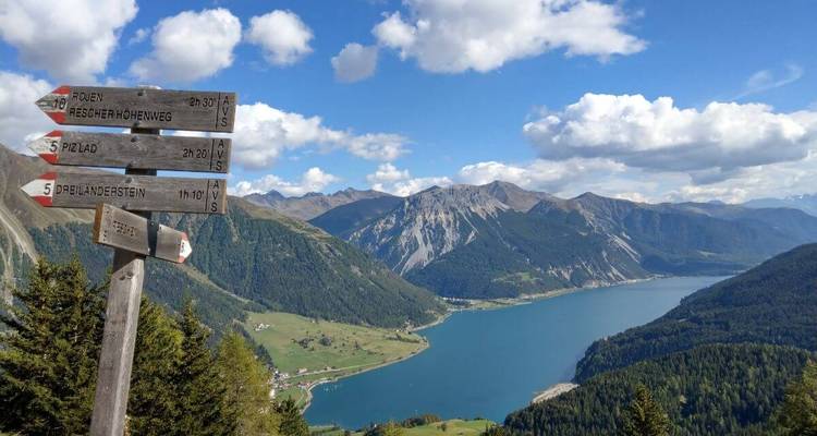 Una señal direccional con vista a un lago y montañas.