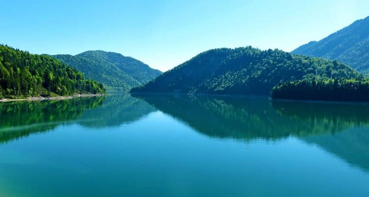 Heldere blauwe meer dat de omringende groene bergen weerkaatst.