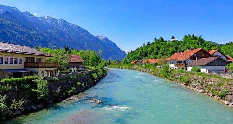 Rivier met alpine huizen en besneeuwde bergen op de achtergrond.