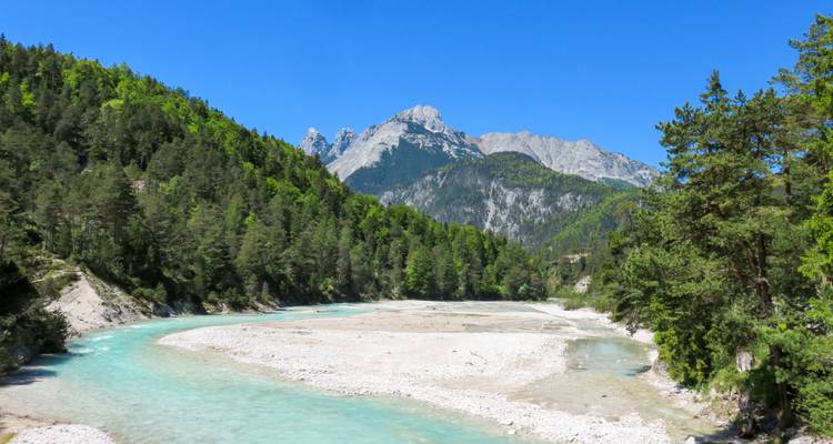 Turquoise bergrivier die kronkelt door een beboste vallei met kalksteentoppen erboven.