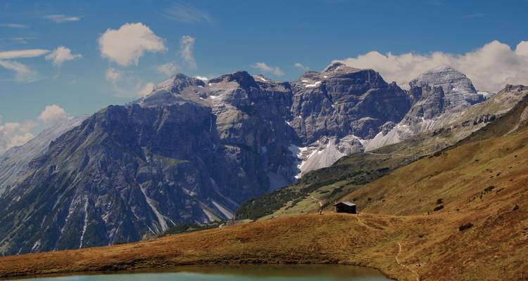 Bergketen met besneeuwde toppen en een klein alpenmeer.