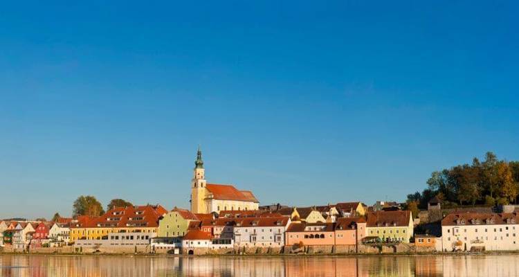 Bunte Stadt entlang eines Flusses mit einem markanten Uhrenturm.