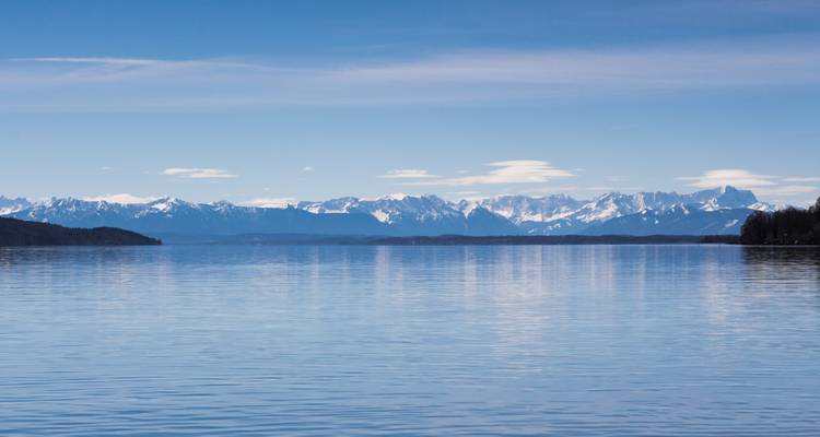 Vaste lac avec des montagnes enneigées au loin.