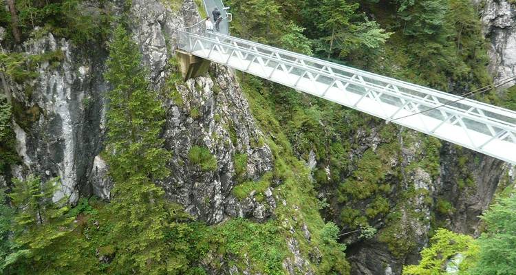 Pont de verre au-dessus d'une gorge avec une personne qui marche.