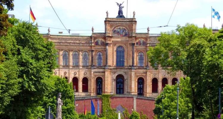Groot overheidsgebouw omgeven door groene bomen.