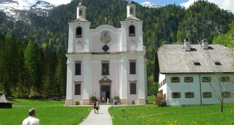 Un groupe de personnes près d'une église avec un arrière-plan montagneux.