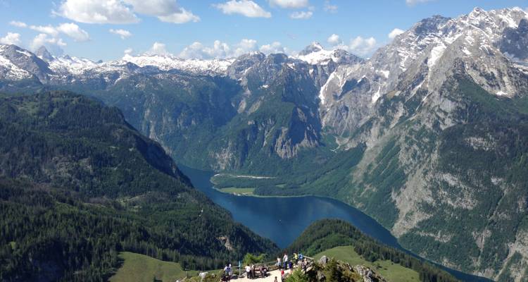 Vue panoramique des montagnes avec des touristes surplombant un lac.