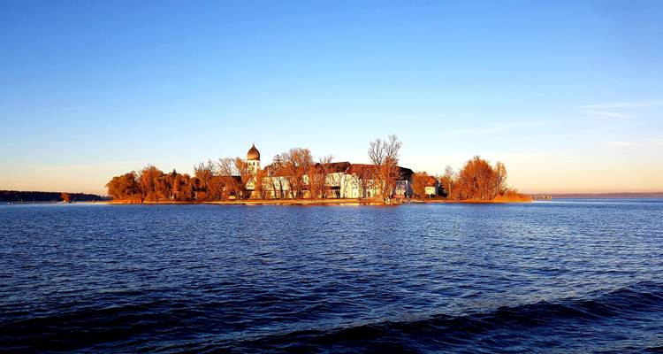 An island with a historic building surrounded by calm waters.