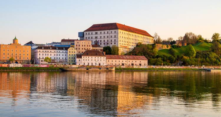 Historic building by a river during sunset.