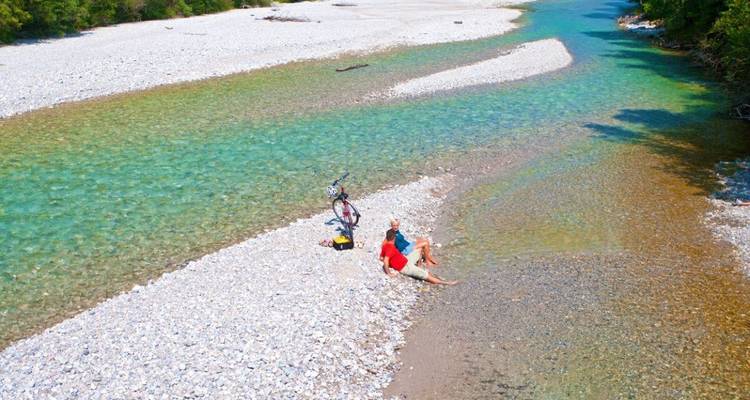 Des gens qui se détendent au bord d'une rivière peu profonde aux eaux turquoise éclatantes.