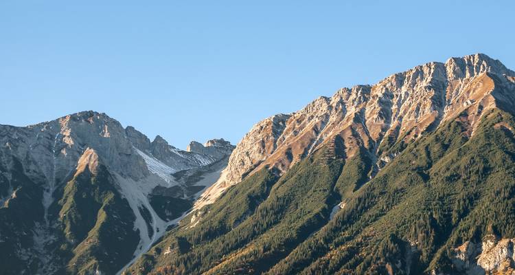 Gebirgszug mit zerklüfteten Geländeformen vor einem blauen Himmel.