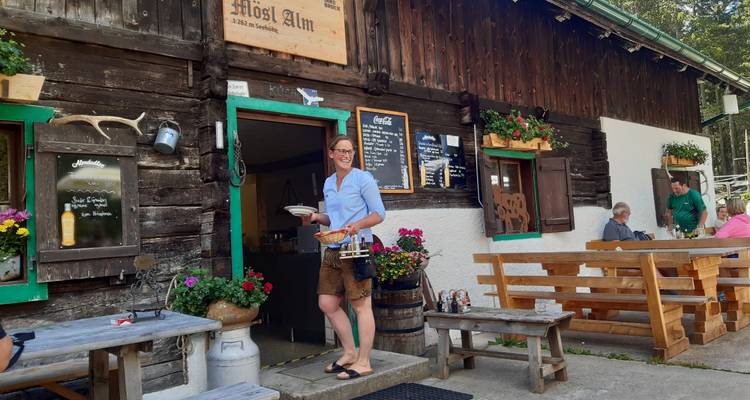Person, die Essen vor einer Holztaverne mit rustikaler Einrichtung serviert.