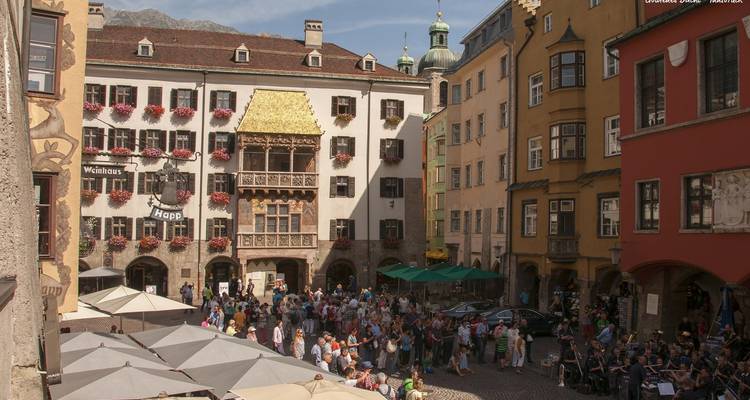 Crowded square with colorful historic buildings and people walking around.