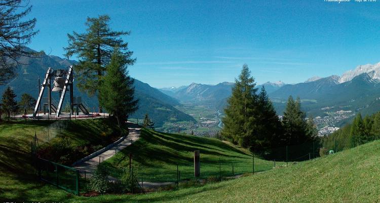 Une vue panoramique d'une vallée avec une végétation luxuriante et des montagnes au loin.
