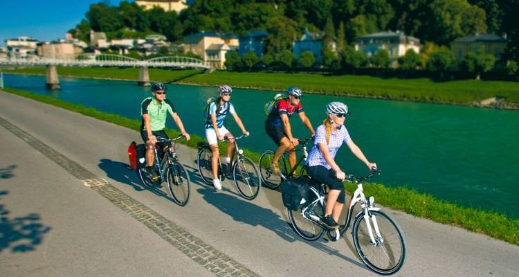 Gruppe von Radfahrern, die an einem Fluss entlangfahren.