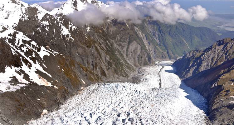 Aerial view of a large glacier surrounded by snow-capped mountains.