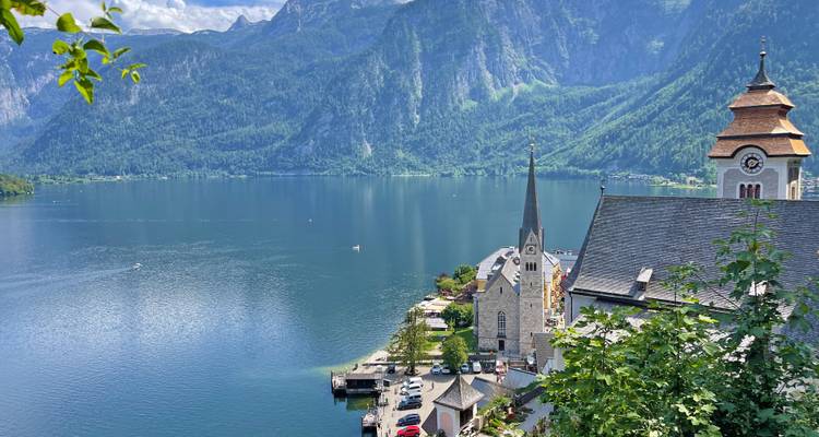 Picturesque lakeside village with mountains and a church steeple.