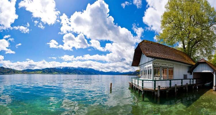 A lakeside scene with a charming house and panoramic views.