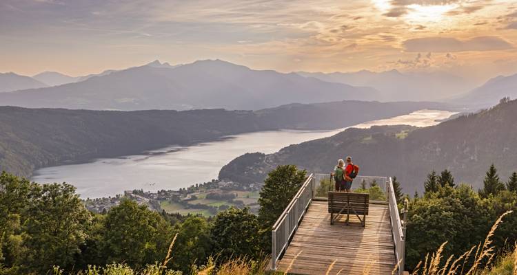 Schilderachtig uitkijkplatform hoog boven een kronkelend meer met bergachtergrond tijdens het gouden uur.