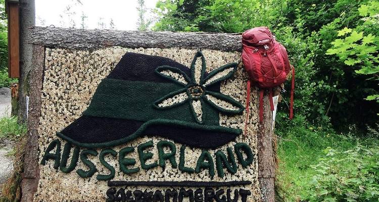 Bord met de tekst 'Ausseerland' met een rode rugzak ernaast.
