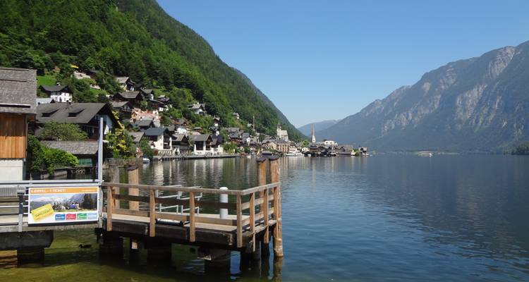 Un village alpin pittoresque au bord d'un lac avec des montagnes sous un ciel bleu dégagé.