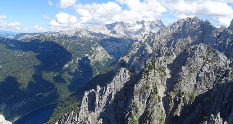 Vue panoramique de pics montagneux escarpés avec des zones boisées en contrebas.