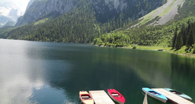 Un lac serein avec des kayaks colorés sur le quai et des montagnes à l'arrière-plan.