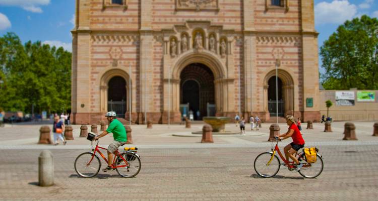 Radfahrer, die an einem großartigen historischen Gebäude mit kunstvoller Architektur vorbeifahren.