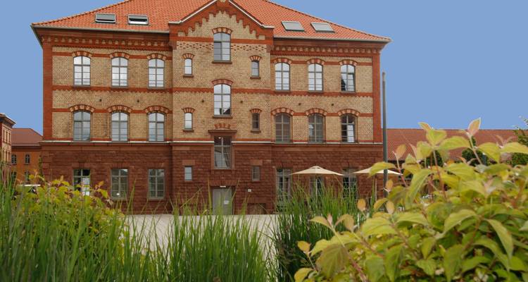 Bâtiment historique en brique avec jardin bien entretenu.