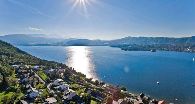 Une vue ensoleillée sur un lac avec des bateaux et des maisons au bord du rivage.