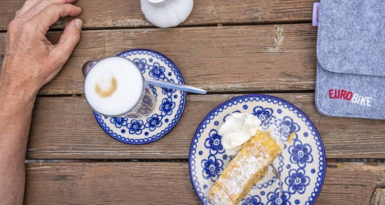 Table with a cup of coffee and a slice of cake.