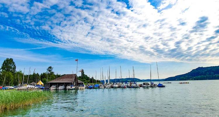 Vue au bord du lac avec des bateaux et un ciel bleu.