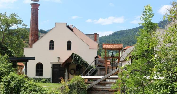 A scenic view of a historic building with a chimney surrounded by greenery.