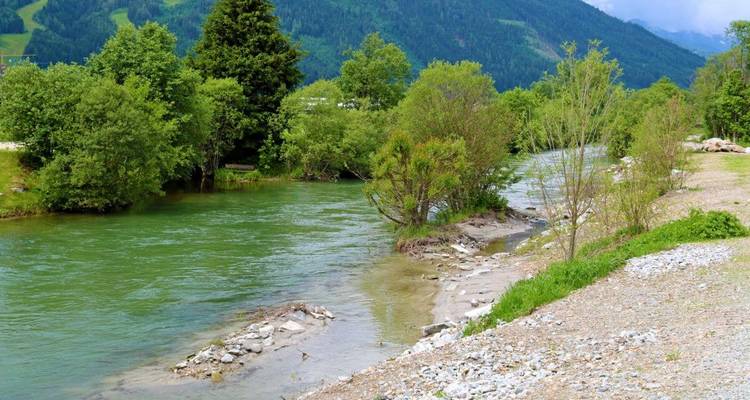 A river flowing through a landscape with mountains in the background.