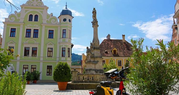 A historical town square with colorful buildings and a fountain.
