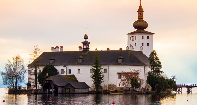 Historic building with towers located on a misty lake.