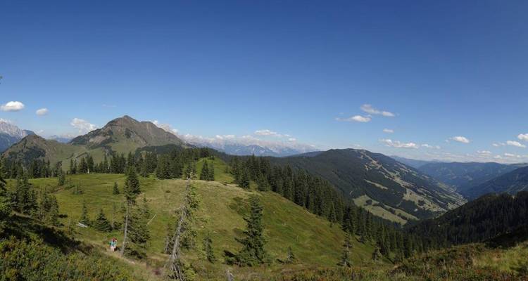 Vaste paysage de montagne avec un randonneur solitaire.
