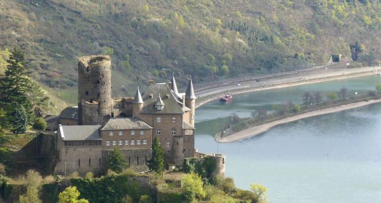 Kasteel met uitzicht op een rivierbocht te midden van weelderige heuvels.