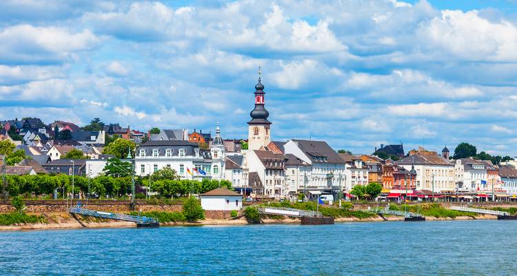 Pittoresk stadje met een kerk aan een rivier onder blauwe luchten.