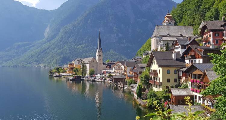 Iconische ansichtkaartview van het dorpje Hallstatt met kerktoren en meer tegen torenhoge kliffen.