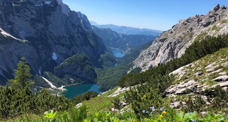 Uitgestrekte alpenvallei met twee blauwe meren bekeken tussen dramatische rotswanden.