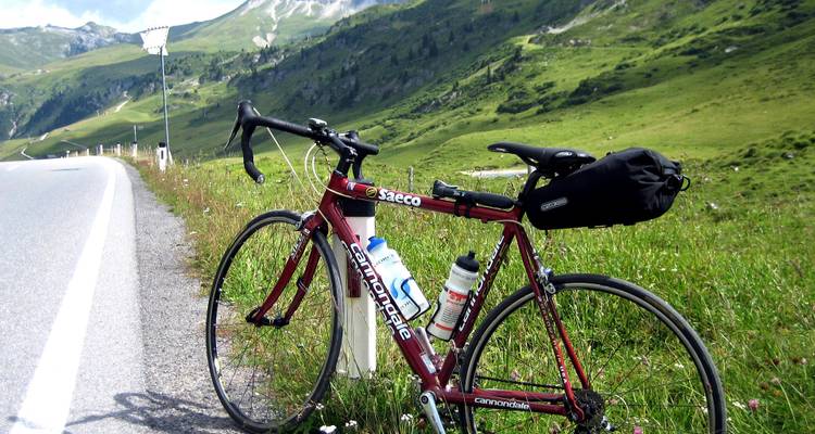 Rotes Straßenfahrrad geparkt mit Bergen im Hintergrund sichtbar.