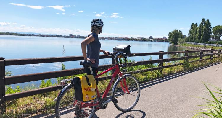 Cyclist pausing on a pathway beside a large lake.