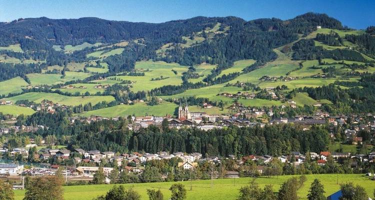 A picturesque town nestled in a lush valley surrounded by mountains.