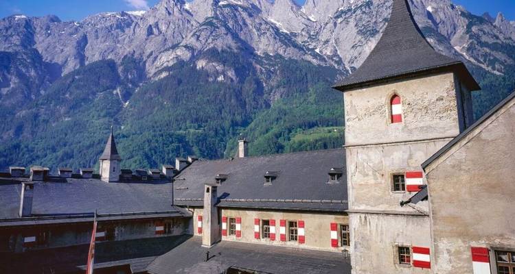 Historic building with mountainous backdrop under a blue sky.