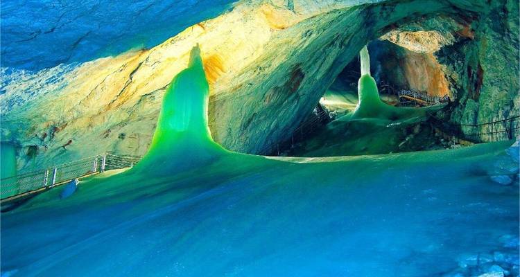 Une grotte de glace avec des formations saisissantes illuminées d'une lumière bleue et verte.