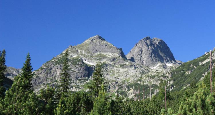 Two mountain peaks with clear blue sky above.