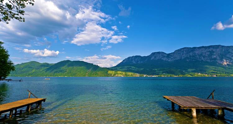Vue au bord du lac avec des montagnes lointaines sous un ciel bleu dégagé.