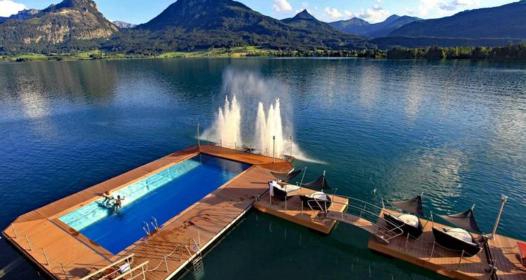 Une piscine flottante et une petite jetée avec des montagnes en arrière-plan.